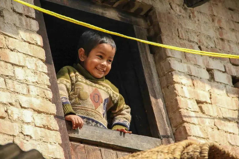 Niño nepalí sonriendo asomado a la ventana